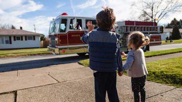 孩子们在练习消防疏散计划后向消防车挥手.