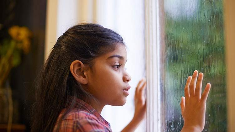 女孩安全地望着下雨的窗外